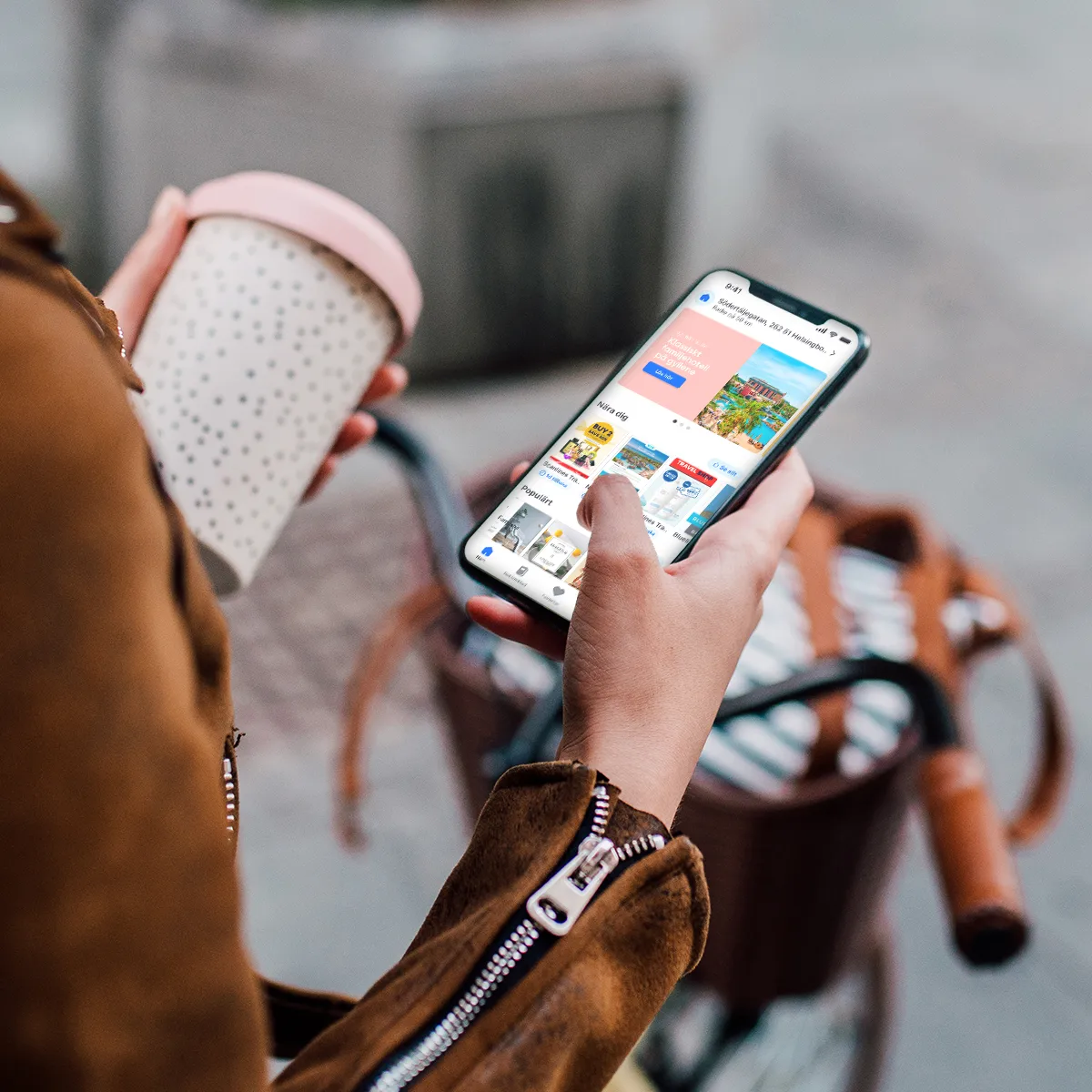 Person som håller en kaffemugg och använder Dayli-appen på en smartphone medan personen står vid en cykel